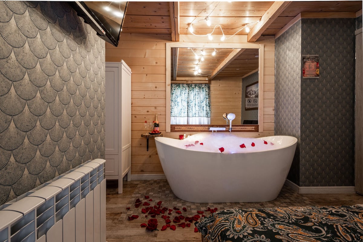 A bathroom with a freestanding bathtub, wooden walls, and a patterned floor.