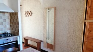 A kitchen with a stove, a wooden bench, and a wall-mounted mirror.