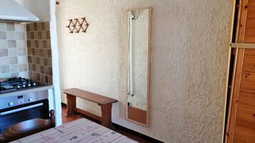 A kitchen with a stove, a wooden bench, and a wall-mounted mirror.