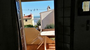 A view from an open door to a balcony with a tiled floor, a chair, and a table.