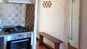 A kitchen with a gas stove, oven, and white textured walls.