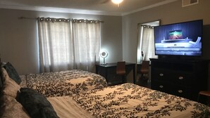 Habitación de hotel con dos camas, televisión, escritorio y espejo.