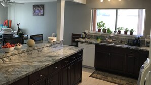 Una cocina moderna con armarios oscuros, una encimera de granito y una ventana con plantas en macetas.