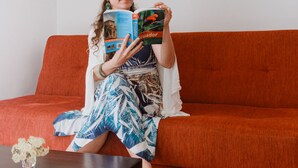 A person sitting on an orange sofa, reading a book. - Hotel Galapagos Suites (Puerto Ayora)