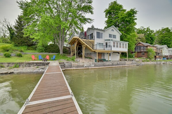 A wooden dock leading to a house by a calm body of water.