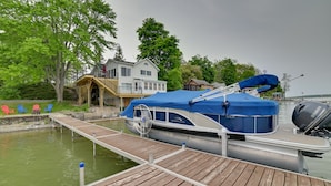 Um cais com um barco, uma casa e uma fileira de cadeiras Adirondack coloridas.
