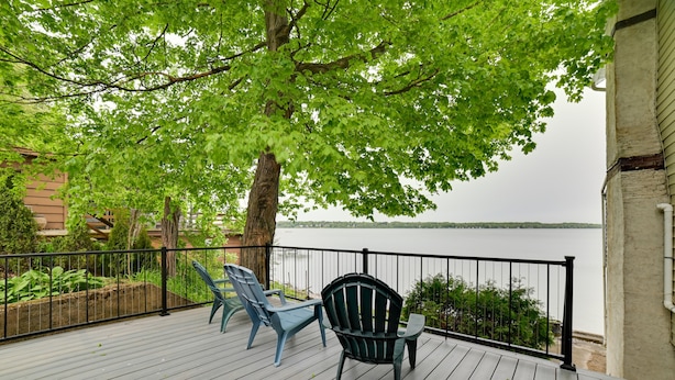 Um terraço com duas cadeiras e uma mesa, com vista para a água.