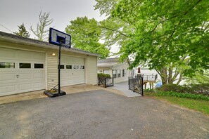 A residential garage with a basketball hoop, a covered driveway, and a view of a lake.