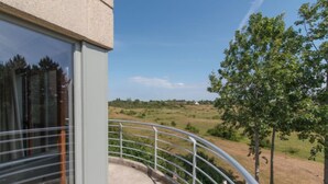 A balcony with a view of a rural landscape, including fields and trees.
