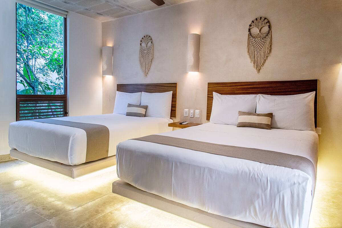 Two double beds with wooden headboards, white bedding, and wall-mounted sconces.