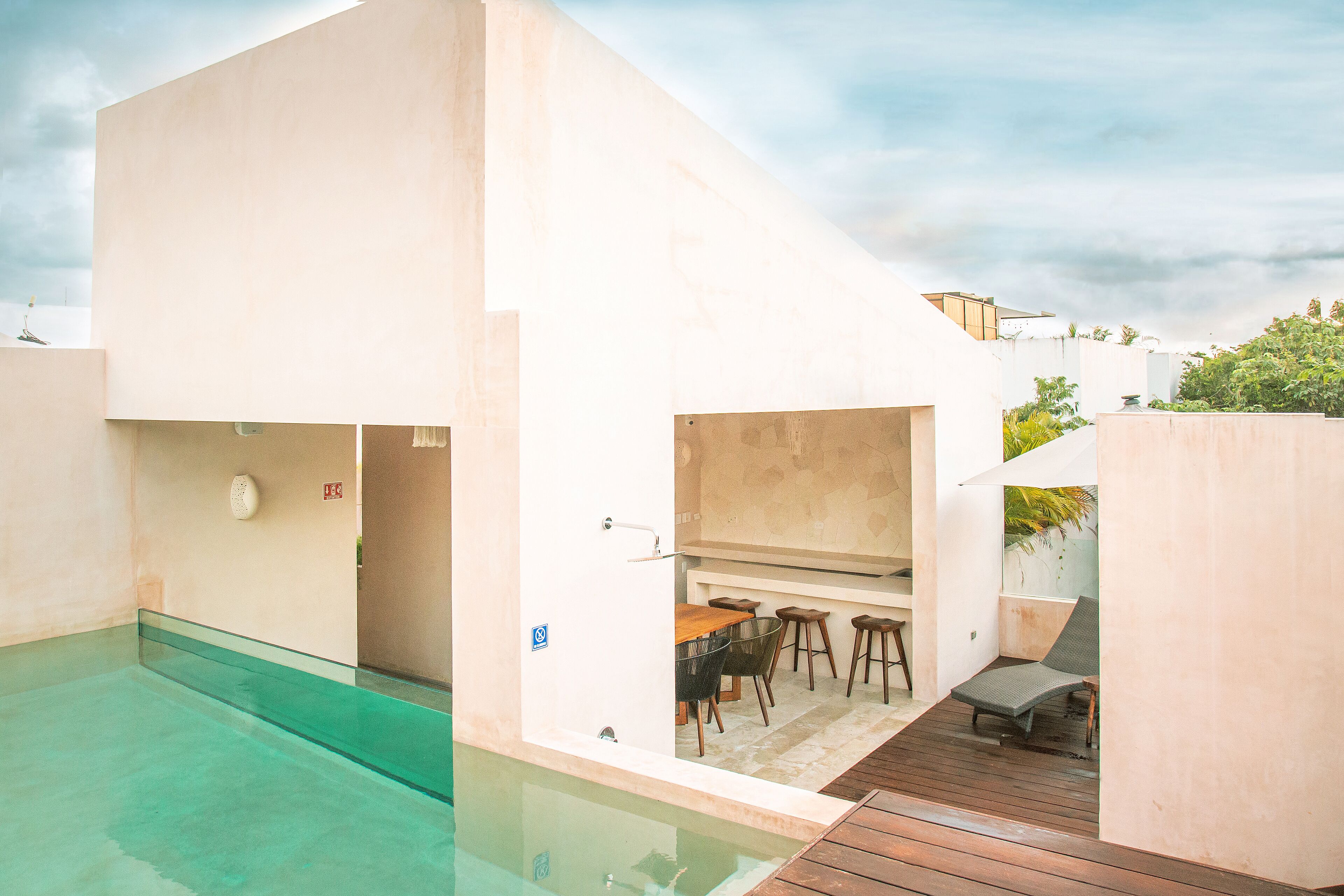 A modern outdoor pool area with a wooden deck, a bar, and seating.