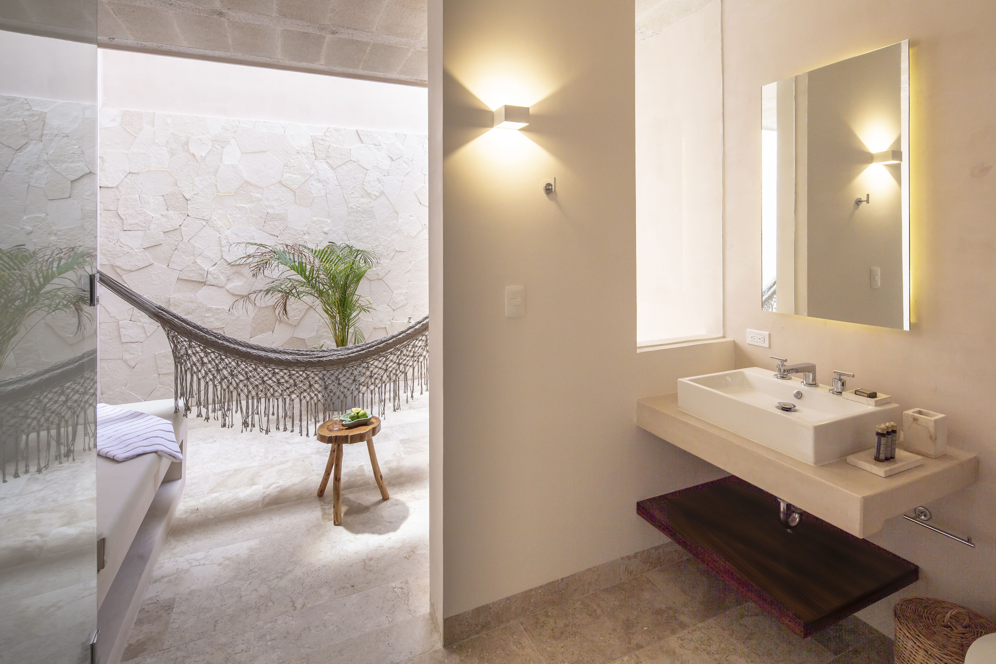 Un baño con pared de piedra, una hamaca, un lavabo y un espejo.