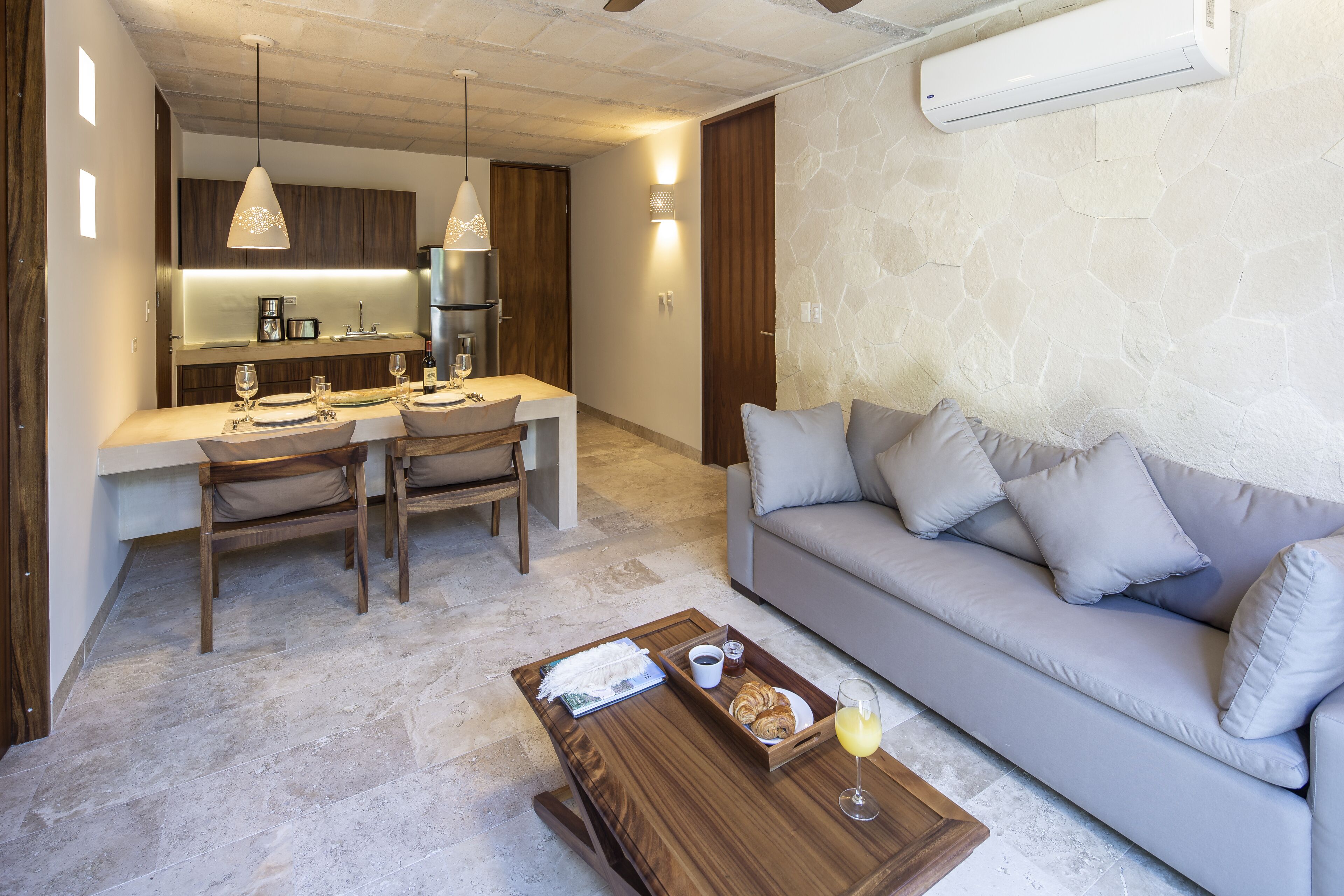 Ein modernes Wohnzimmer mit einer Couch, einem Esstisch und Stühlen. Auf dem Couchtisch steht eine Platte mit Speisen und Getränken.