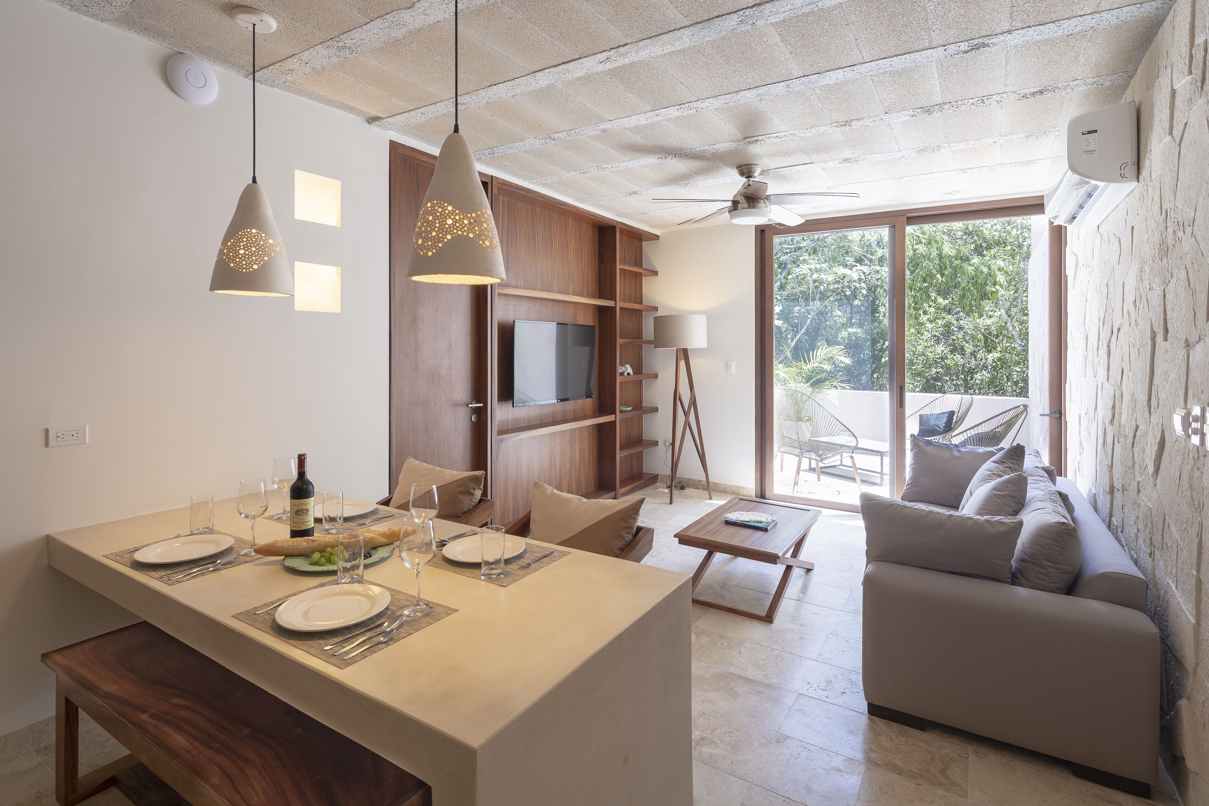 A modern kitchen with a dining area, a sofa, and a TV.