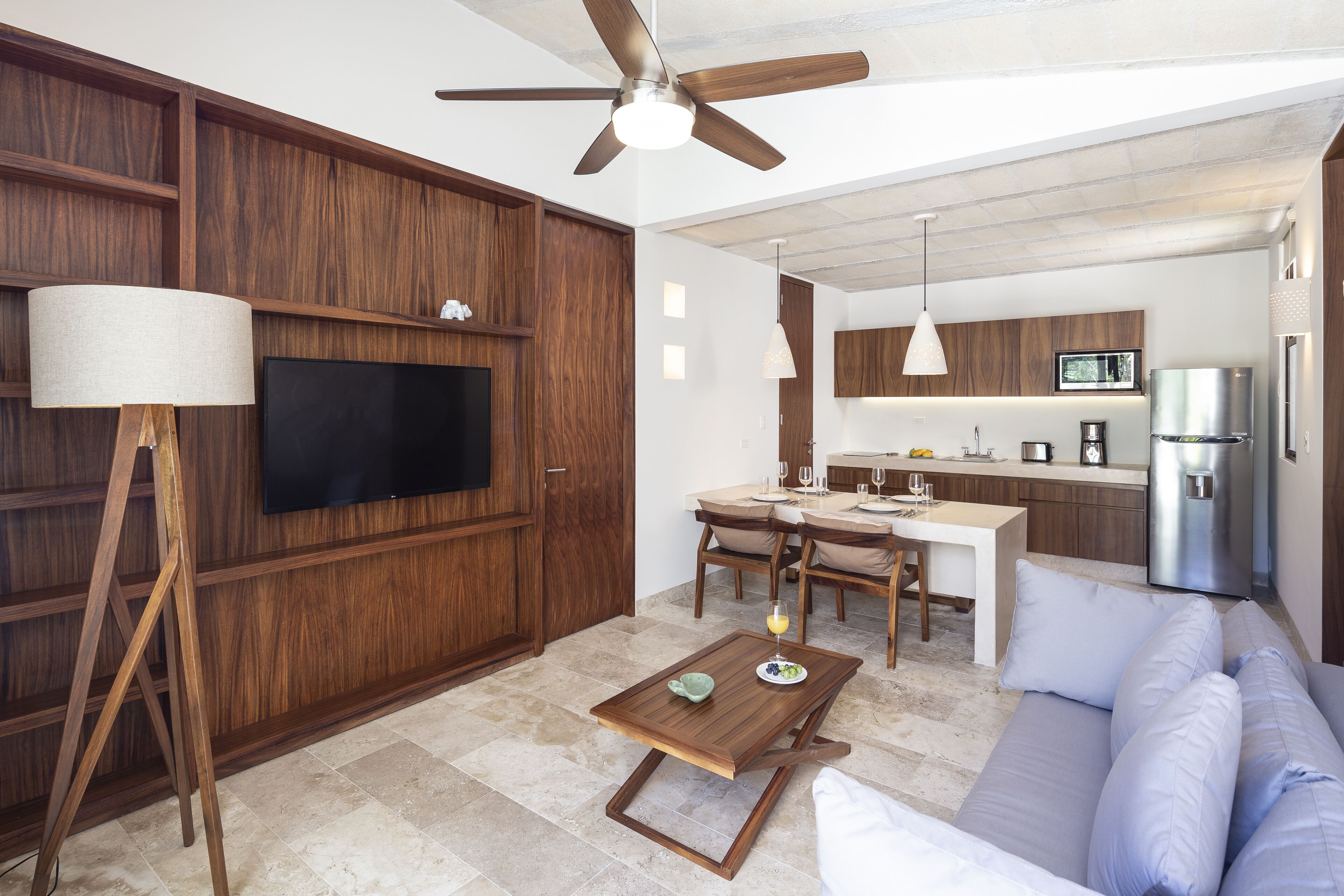 A modern living room with a TV, wooden cabinets, a sofa, and a dining area with a table and chairs.
