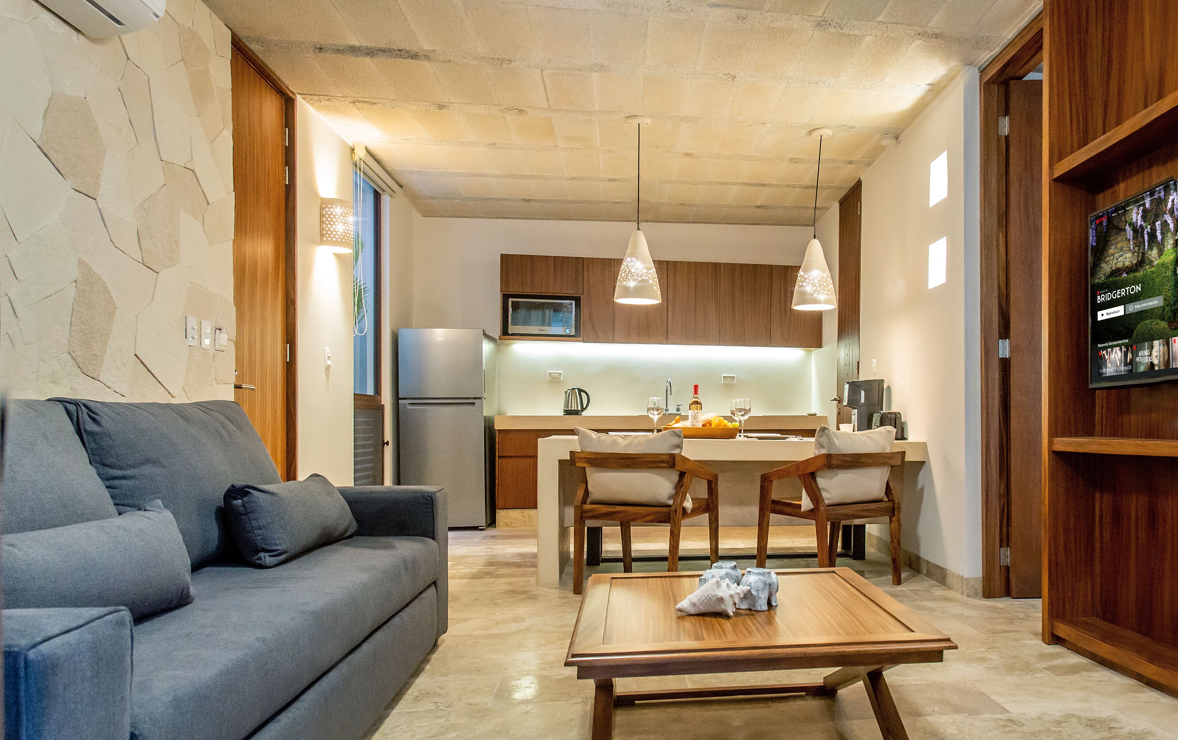 Ein modernes Wohnzimmer mit grauem Sofa, Holztisch und Pendelleuchten.