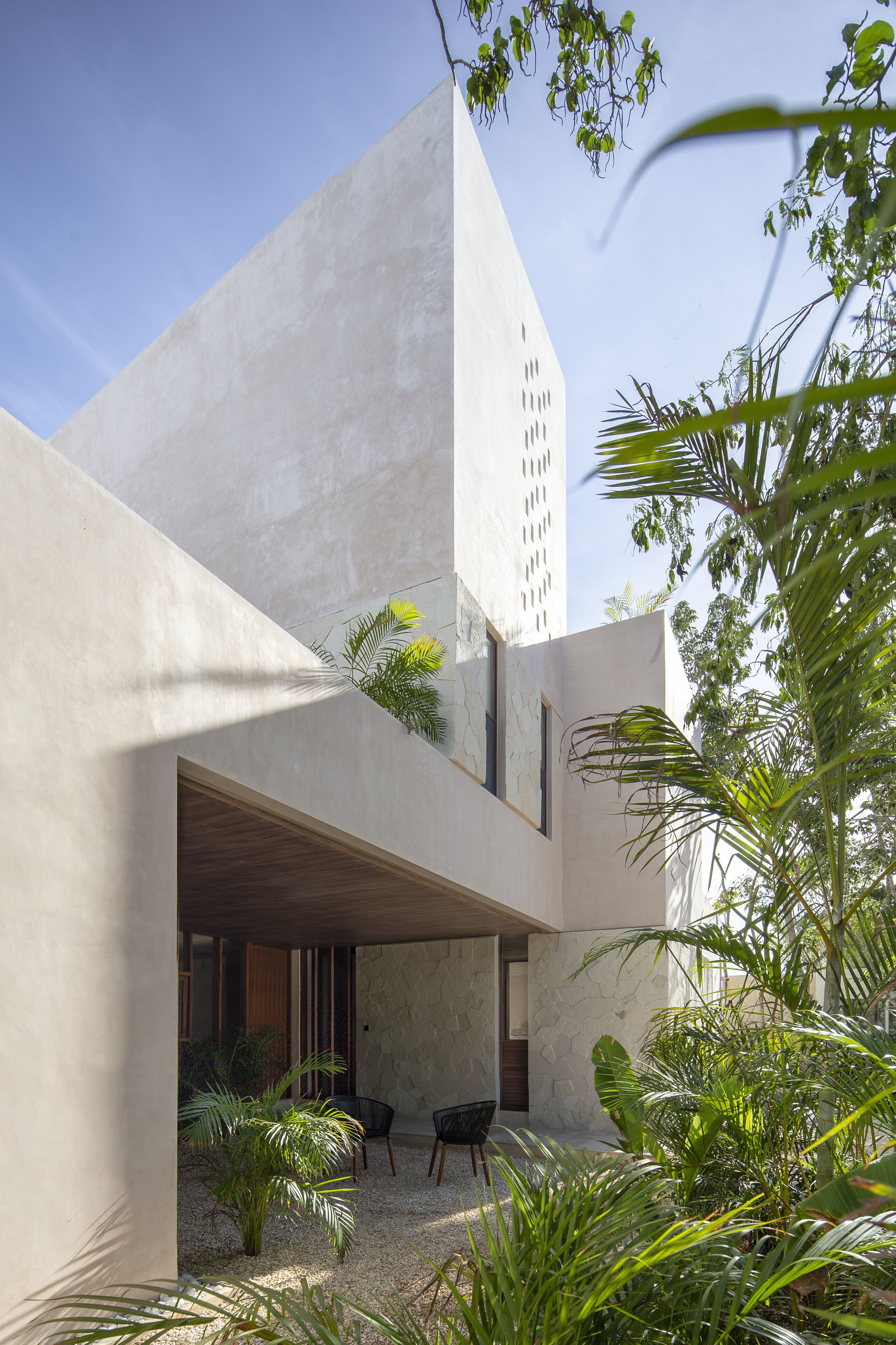 A modern building with a concrete exterior and a covered outdoor seating area with plants.