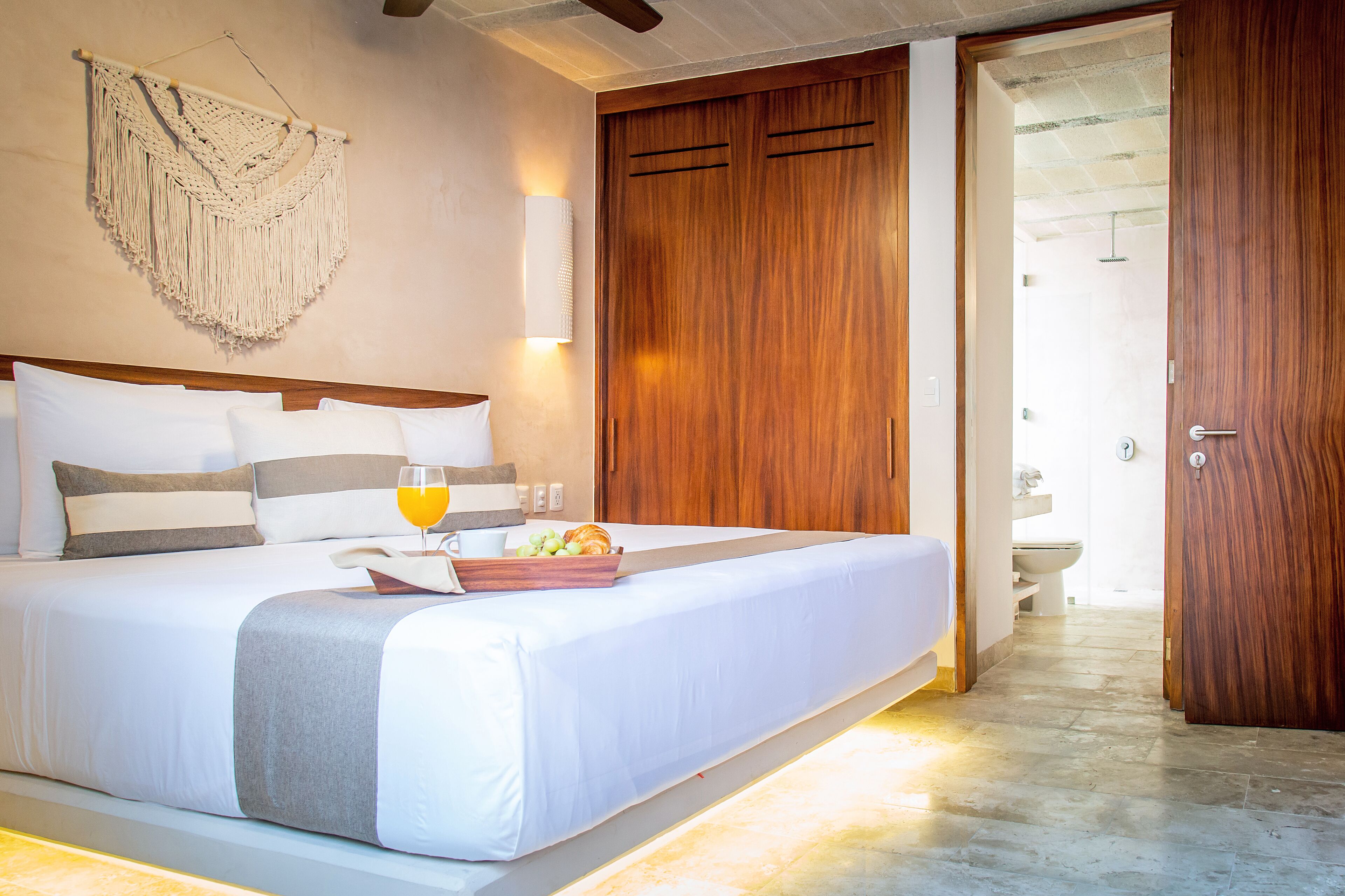 A hotel room with a large bed, wooden wardrobe, and a bathroom visible through an open door.