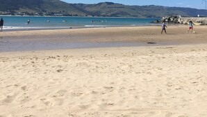 Una spiaggia con cielo sereno, acqua calma e colline all'orizzonte.