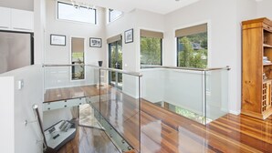 Un interno moderno con ringhiera in vetro, pavimento in legno e vista sul verde.