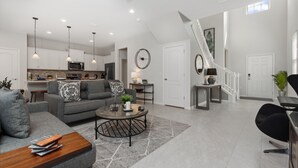 Ein großzügiger Wohnbereich mit grauem Sofa, einem Couchtisch und einer Treppe, die in eine obere Etage führt.