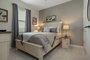 Une chambre à coucher avec un lit, des tables de chevet, une commode et des rideaux.