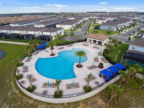 Un quartier résidentiel doté d’une piscine, entourée de chaises longues et de palmiers.