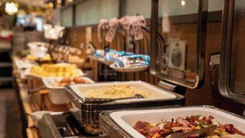 A buffet with various food options, including meats and baked goods.