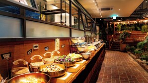 A buffet with various dishes and a brick floor. - Staz Hotel Premier Dongtan (Hwaseong)