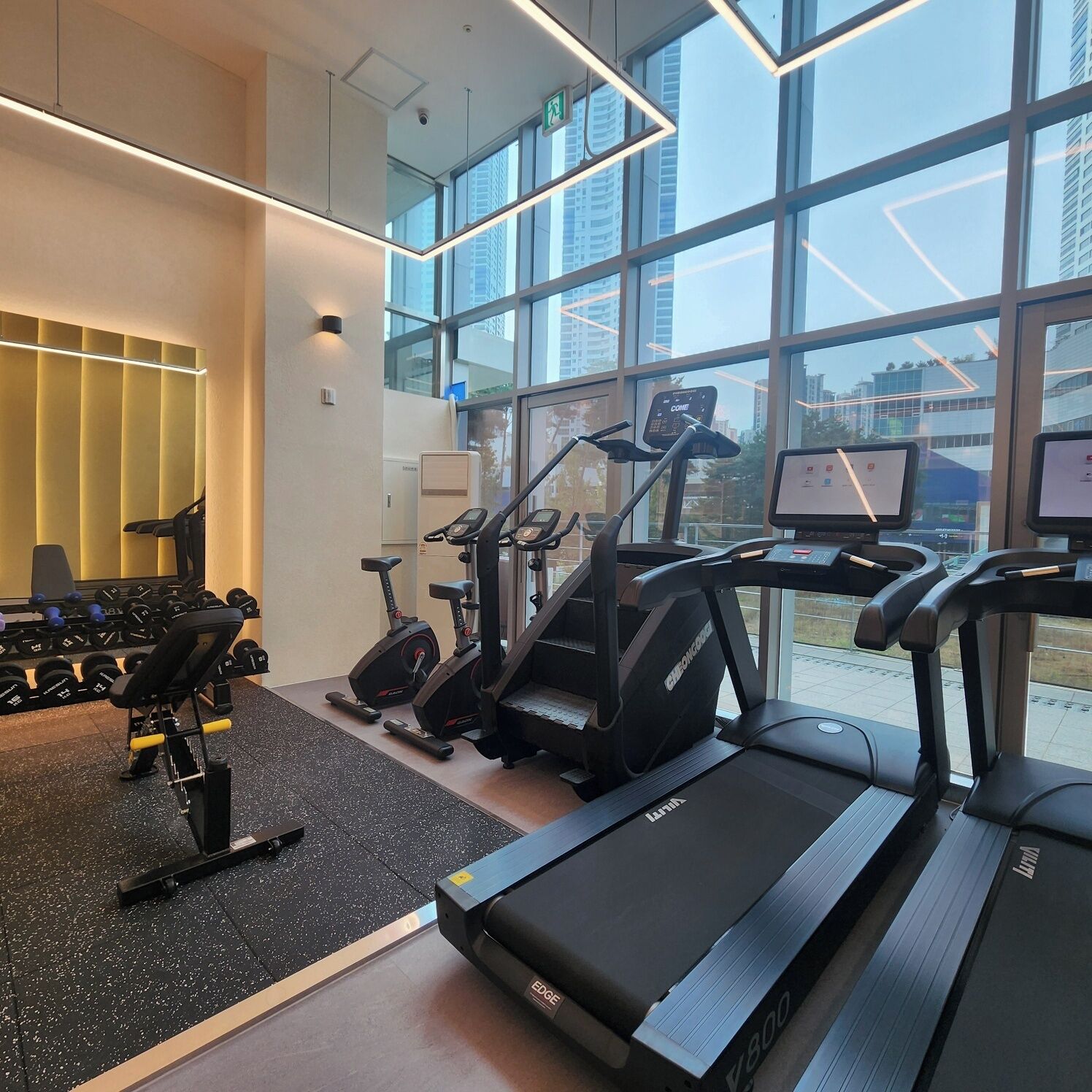 Une salle de sport moderne équipée de tapis de course, de vélos d’appartement et d’appareils de musculation.