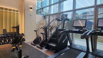 Une salle de sport moderne équipée de tapis de course, de vélos d’appartement et d’appareils de musculation.