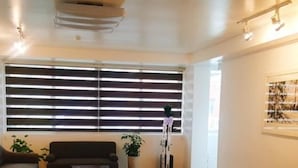 Amplia sala de estar con un sofá oscuro, una mesita de centro y una planta en maceta.