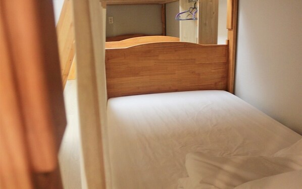 A small, single-bed room with a wooden headboard and a plain mattress. - Syuming Guesthouse - Hostel (Gangneung)