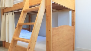 Una cama litera de madera con escalera, colchón y cortinas.