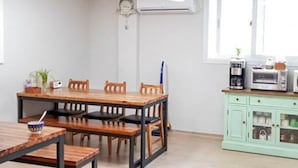 Un comedor con una mesa y sillas de madera, una planta pequeña y un reloj en la pared.