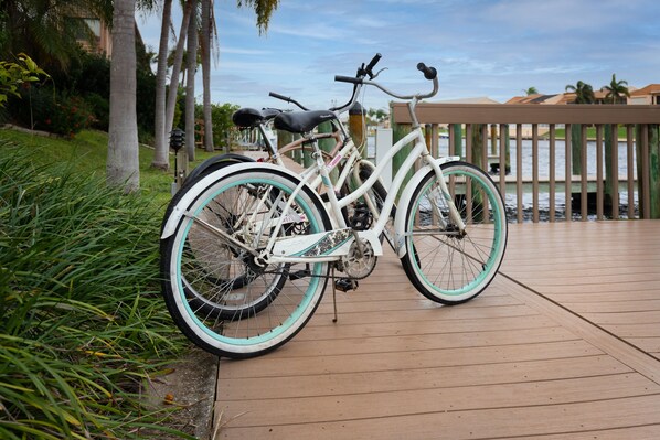 A white bicycle with turquoise rims parked on a wooden deck. - Enchanting tropical waterfront villa with boat slip, bikes, kayaks heated  pool! (Cape Coral)