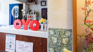 A reception desk with a large 'OYO' sign, a clock, and a decorative wall with a floral pattern. - Tabist Business Hotel Chitose Kashiwazaki (Kashiwazaki)