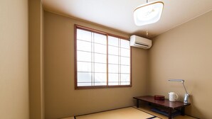A room with tatami flooring, a shoji screen, a small table with a kettle, and an air conditioning unit. - Tabist Business Hotel Chitose Kashiwazaki (Kashiwazaki)