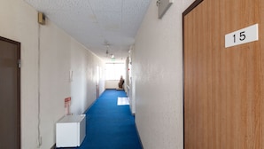 A hallway with a blue carpet, white walls, and a wooden door marked with the number 15. - Tabist Business Hotel Chitose Kashiwazaki (Kashiwazaki)