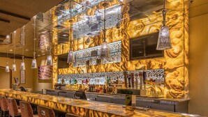 A bar area with a marble countertop, multiple hanging light fixtures, and a variety of bottles and glasses on shelves. - Master Bedroom at Marriott Grand Chateau (Las Vegas)