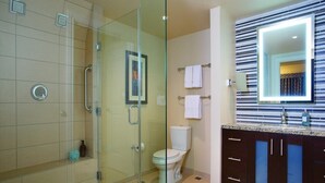 A modern bathroom with a glass shower enclosure, a toilet, a vanity with a mirror, and a sink. - Master Bedroom at Marriott Grand Chateau (Las Vegas)