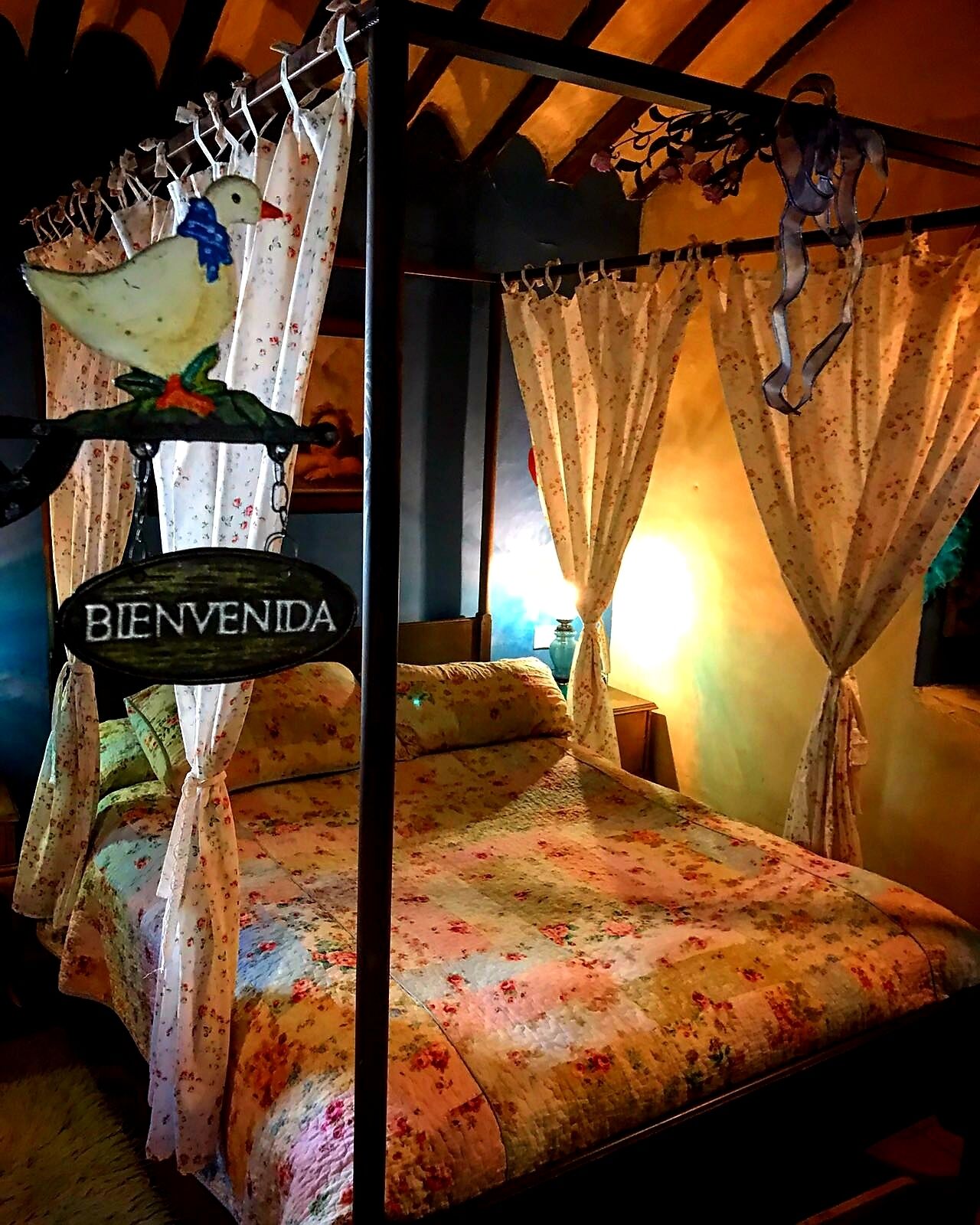Una cama con ropa de cama floral y un cartel que dice 'BIENVENIDA' encima.