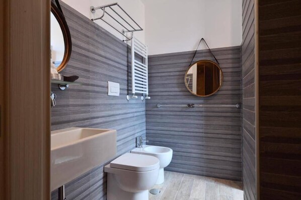 A modern bathroom with a large sink, two toilets, and a mirror. - Veneto Suite Rome (Rome)
