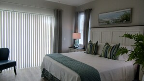 A bedroom with a large bed, a desk, a chair, a lamp, and a window with blinds. - Stay & Play: Pet Friendly Extended Stay for Sports Travel
Covered Parking (Myrtle Beach)