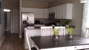 A modern kitchen with white cabinetry, stainless steel appliances, and a dining table with two potted plants. - Stay & Play: Pet Friendly Extended Stay for Sports Travel
Covered Parking (Myrtle Beach)
