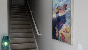 A staircase with wooden steps and a handrail, leading to a landing with a painting of a boat on a beach. - Stay & Play: Pet Friendly Extended Stay for Sports Travel
Covered Parking (Myrtle Beach)