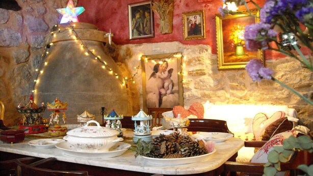A dining area with a stone wall, a wooden table set with plates, a large decorative lantern, and a flower arrangement. - Rural house the Fifth of Malu - Romantic getaway to Cuenca (Valeria)