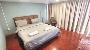 Una habitación de hotel con una cama, una silla, una lámpara de pie y una cortina.