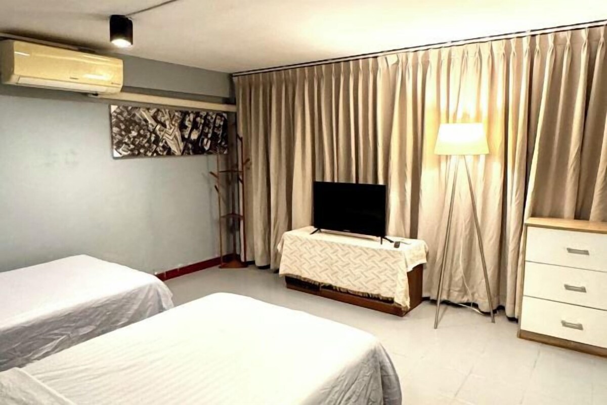 Hotellihuone, jossa on kaksi sänkyä, televisio, työpöytä ja lamppu.