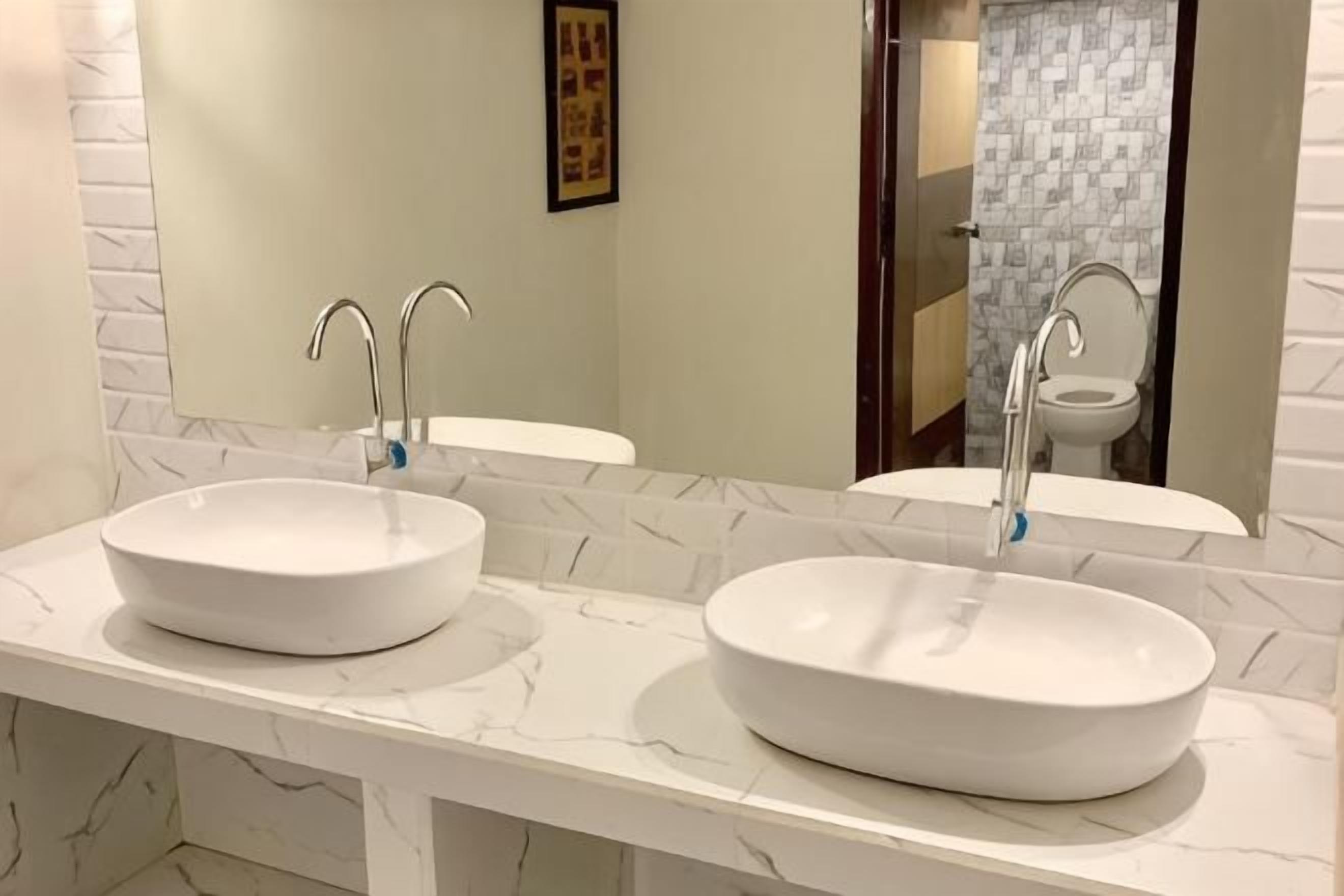 Un baño con dos lavamanos blancos, un espejo y una pared con azulejos.